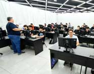 Professor orienta alunos do curso de Ciência da Computação em aula prática no laboratório de informática, focando em desenvolvimento e aprendizado de programação e algoritmos.