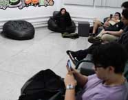 Alunos de Ciência da Computação em momento de descanso e socialização na sala de convivência da faculdade, com pufes e espaço descontraído para interação.