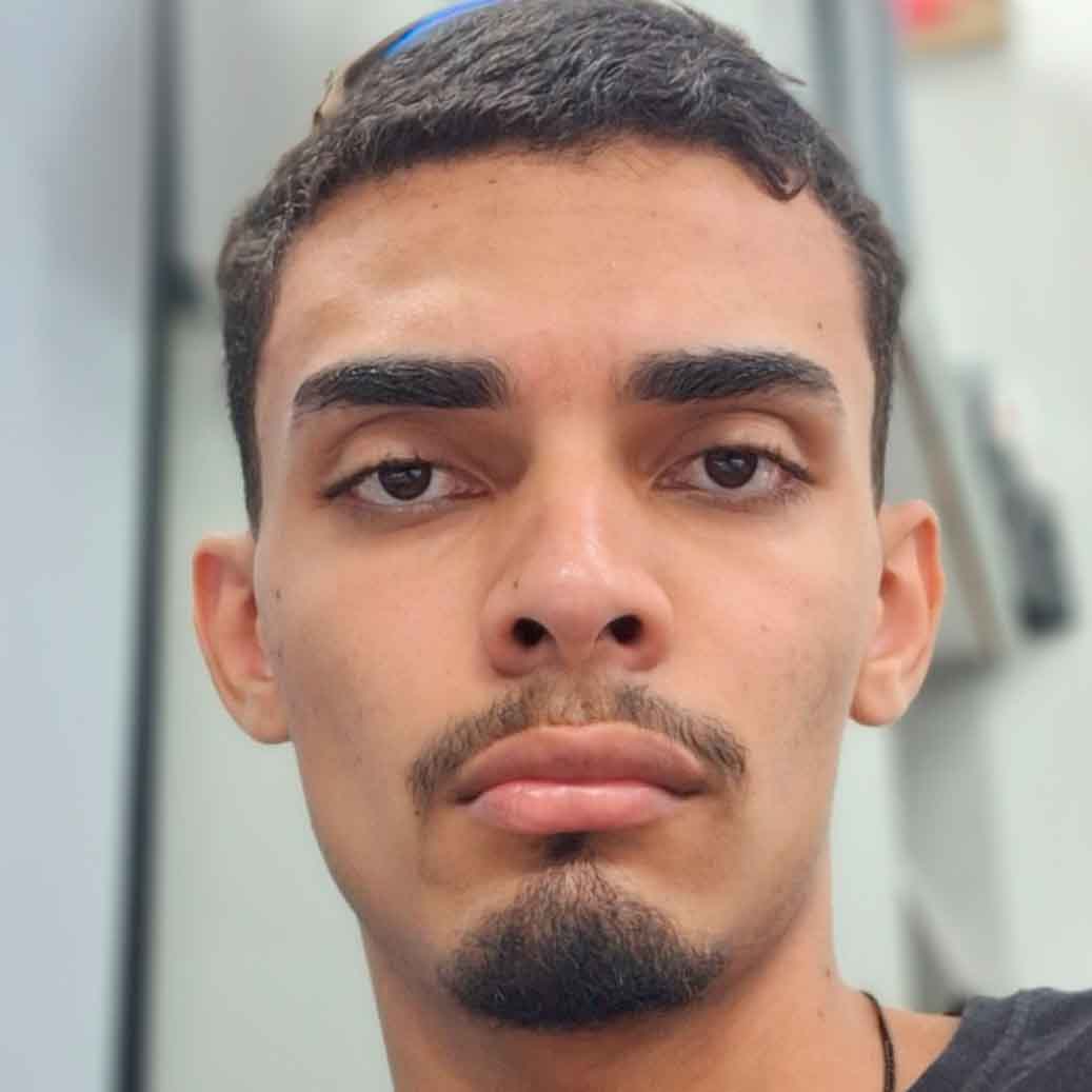Evandro, aluno de Ciências Biológicas - Licenciatura, posando em um ambiente interno com um fundo claro. Ele tem cabelos curtos e barba, com uma expressão neutra.