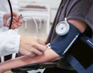 Profissional de saúde ou aluno de Enfermagem aferindo a pressão arterial de um paciente, utilizando esfigmomanômetro manual e estetoscópio.