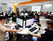 Alunos do curso de Análise e Desenvolvimento de Sistemas em aula prática no laboratório de criação, trabalhando colaborativamente em computadores para desenvolvimento de software e projetos.