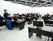 Professor orienta alunos de Análise e Desenvolvimento de Sistemas em aula prática no laboratório de informática, focando em programação e desenvolvimento de soluções.