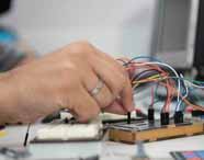 "Aluno de Análise e Desenvolvimento de Sistemas trabalhando com microcontroladores e eletrônica em laboratório, conectando componentes para prototipagem de sistemas embarcados e IoT.  "