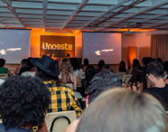 Auditório da Faculdade de História com alunos assistindo a uma palestra ou evento, com o logo da Unoeste projetado no telão.