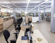 Interior da biblioteca da Faculdade de História, com prateleiras de livros, mesas de estudo e computadores, oferecendo recursos para pesquisa histórica.