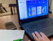 Pessoa acessando a biblioteca virtual da Faculdade de História em Presidente Prudente em um notebook, utilizando recursos digitais para pesquisa e estudo.