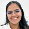 Imagem de Raissa, aluna do curso de enfermagem no campus Guarujá, trajando um jaleco branco. O fundo é claro, indicando um ambiente interno bem iluminado, como uma sala de aula ou laboratório. A composição reflete um espaço propício para o aprendizado e desenvolvimento acadêmico.