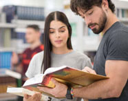 Alunos da Unoeste na biblioteca do campus de Jaú explorando livros e realizando atividades de pesquisa. 
