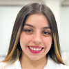 Ana, aluna do curso de biomedicina no campus Jaú, vestindo jaleco branco. O fundo sugere um laboratório ou sala de aula técnica, projetado para práticas acadêmicas e atividades científicas. A composição da imagem transmite organização, profissionalismo e foco nos estudos, refletindo o ambiente de aprendizado essencial para a formação na biomedicina.