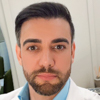 Imagem de Rodrigo, egresso do curso de medicina no campus Presidente Prudente, trajando jaleco branco. O fundo claro reforça o ambiente acadêmico e técnico voltado para a área da saúde. A composição reflete profissionalismo e dedicação.