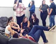 Faculdade de administração em Jaú, área de convivência com estudantes sentados em bancos, conversando e interagindo em um espaço moderno e acolhedor. Plantas decorativas e iluminação natural compõem o ambiente, que promove socialização, troca de experiências e integração entre alunos de administração no cotidiano do campus.