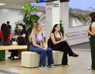 Faculdade de administração em Jaú, área de convivência com puffs: grupo de alunos sentados e deitados em puffs pretos, conversando e sorrindo em clima descontraído. O espaço interno valoriza o bem-estar, a interação e a construção de amizades durante a vida universitária, promovendo o equilíbrio entre estudo e momentos de lazer.