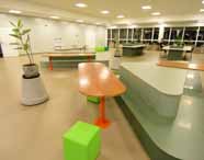 Faculdade de administração em Jaú estrutura: espaço interno amplo e moderno, com mesas, bancos coloridos, plantas decorativas e iluminação artificial. O ambiente é pensado para convivência, estudos e refeições, promovendo conforto, socialização e bem-estar aos estudantes de administração durante o dia a dia no campus.