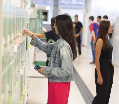 Perfil profissional administração Jaú: estudantes em um corredor de armários, interagindo com os compartimentos e circulando pelo espaço bem iluminado. A cena destaca o cotidiano acadêmico, a organização pessoal dos alunos e o ambiente moderno da instituição, reforçando a autonomia, a convivência e a estrutura de apoio oferecida ao estudante de administração em Jaú.