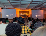 Auditório da Faculdade de Letras Português com alunos assistindo a uma palestra ou evento, com o logo da Unoeste projetado no telão.