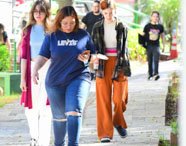 Grupo de estudantes da Faculdade de Letras Português caminhando em área verde do campus, interagindo e aproveitando o ambiente universitário.