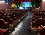 Interior do Teatro César Cava, palco de eventos acadêmicos da Faculdade de Letras Português, com poltronas vazias e palco iluminado.