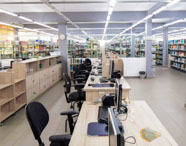 Interior da biblioteca da Faculdade de Letras Inglês, com prateleiras de livros, mesas de estudo e computadores, oferecendo recursos para pesquisa.