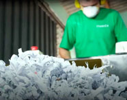 Funcionário da Faculdade de Celulose e Papel operando máquina de reciclagem de papel, com foco em sustentabilidade e gestão de resíduos.