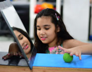 Terapeuta ocupacional ou aluna realizando atendimento infantil, com criança brincando com bola e espelho, focando em desenvolvimento e reabilitação.