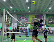 Jogo de vôlei no ginásio de esportes da Faculdade de Terapia Ocupacional em Guarujá, com atletas em ação e torcida nas arquibancadas.