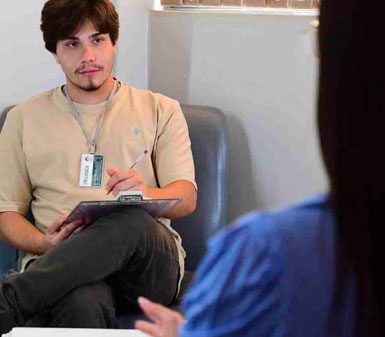 Terapeuta ocupacional ou aluna da Faculdade de Terapia Ocupacional em Guarujá auxiliando criança com bola de exercícios, destacando o perfil profissional do curso.