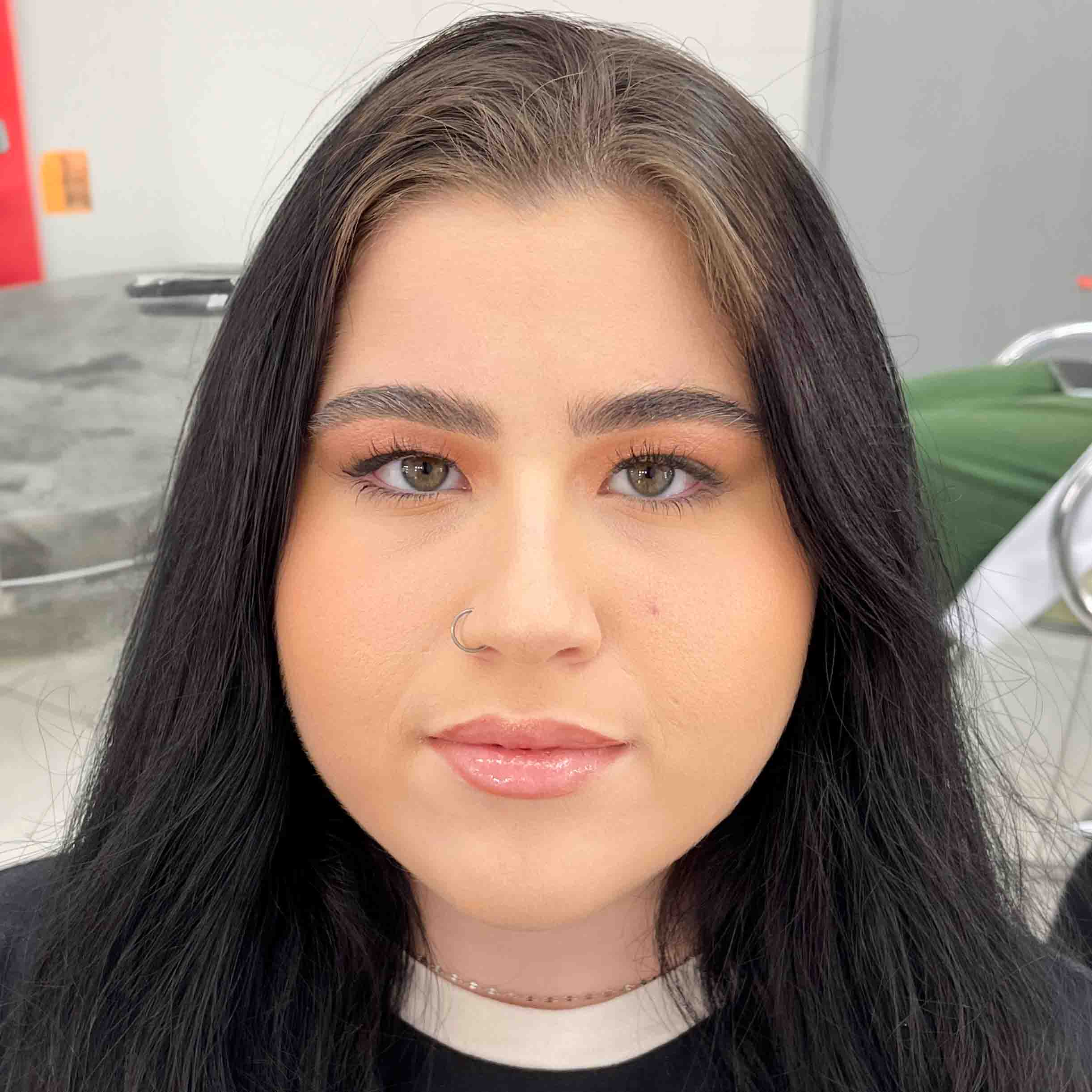 Isabelli, aluna do curso de estética e cosmética, em um ambiente interno com cadeiras e detalhes modernos ao fundo. Ela usa uma blusa escura que contrasta com o cenário claro.