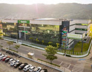 Vista aérea da moderna estrutura da Faculdade de Estética e Cosmética em Guarujá (Unoeste), com painéis solares e amplo estacionamento.