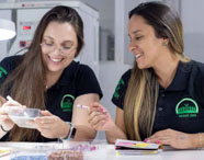 Duas alunas de Agronomia da Faculdade de Agroecologia em Presidente Prudente realizando análise de sementes em laboratório, demonstrando pesquisa e aprendizado prático.