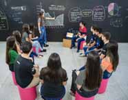 Faculdade de administração em Presidente Prudente, alunos em aula gráficos: turma participa de apresentação interativa, com aluna explicando gráficos no quadro-negro enquanto colegas acompanham atentos. A disposição em círculo favorece a troca de ideias, protagonismo estudantil e o desenvolvimento de habilidades de comunicação e liderança essenciais para o curso de administração.