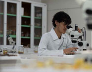 Aluno da Faculdade de Alimentos em laboratório, utilizando microscópio para análise de amostras, com foco em pesquisa e controle de qualidade.