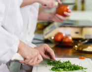 Close-up de mãos picando temperos em laboratório de análise de alimentos da Faculdade de Alimentos, destacando o preparo e a higiene.