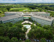 Vista aérea do campus da Faculdade de Aquicultura em Presidente Prudente, com edifícios modernos, áreas verdes e paisagismo, destacando a infraestrutura universitária.