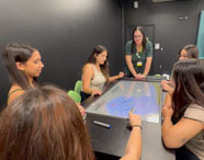 Alunos da Faculdade de Sistemas de Informação em Jaú em atividade na Sala Betha, utilizando mesa interativa para aprendizado colaborativo e tecnológico.