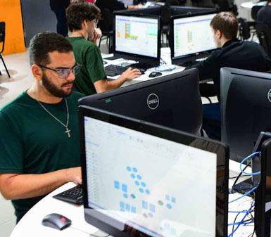 Aluno da Faculdade de Sistemas de Informação em Jaú trabalhando em computador no laboratório, representando o perfil profissional do curso em tecnologia.