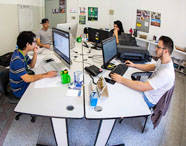 Alunos da Faculdade de Mídias Sociais Digitais trabalhando em agência experimental, utilizando computadores para projetos de comunicação e marketing digital.