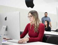 Alunos da Faculdade de Mídias Sociais Digitais em laboratório Mac, utilizando computadores Apple para design gráfico e produção de conteúdo digital.