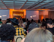 Auditório da Faculdade de Mídias Sociais Digitais com alunos assistindo a uma palestra ou evento, com o logo da Unoeste projetado no telão.