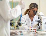 Aluna da Faculdade de Ciências Biológicas em Guarujá realizando análise em laboratório com microscópio, focando em pesquisa e estudo de amostras.