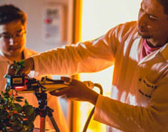 Alunos da Faculdade de Ciências Biológicas em laboratório, analisando plantas com equipamentos de medição, focando em pesquisa e desenvolvimento vegetal.
