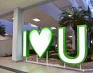 Letreiro I LOVE U (I love Unoeste) em área de convivência da Faculdade de Ciências Biológicas em Guarujá, com palmeiras e arquitetura moderna.