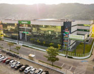 Vista aérea da moderna estrutura da Faculdade de Ciências Biológicas em Guarujá (Unoeste), com painéis solares e amplo estacionamento.