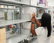 Aluna da Faculdade de Ciências Biológicas em Guarujá selecionando um livro na prateleira da biblioteca, em busca de material para estudo e pesquisa.