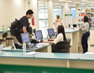Balcão de atendimento da biblioteca da Faculdade de Ciências Biológicas em Guarujá, com alunos e funcionários, oferecendo suporte para pesquisa.