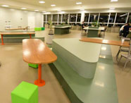 Área de convivência moderna da Faculdade de Agronomia em Jaú, com mesas e bancos, oferecendo espaço para descanso e interação dos alunos.
