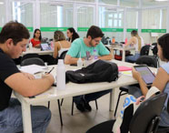 Alunos da Faculdade de Medicina Veterinária em Jaú estudando em mesas coletivas, com notebooks e materiais didáticos, em ambiente de aprendizado.