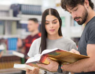 Alunos da Faculdade de Medicina Veterinária em Jaú consultando livros na biblioteca, em ambiente de estudo e pesquisa.