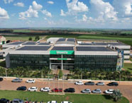 Vista aérea da moderna fachada da Faculdade de Medicina Veterinária em Jaú (Unoeste), com painéis solares e amplo estacionamento.