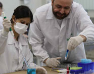 Professor e aluna da Faculdade de Medicina Veterinária em Jaú em aula prática de laboratório, manuseando tubos de ensaio e pipetas para experimentos.
