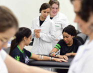 Alunas da Faculdade de Terapia Ocupacional em Jaú realizando testes e práticas com aparelhos em laboratório, aplicando conhecimentos em reabilitação.